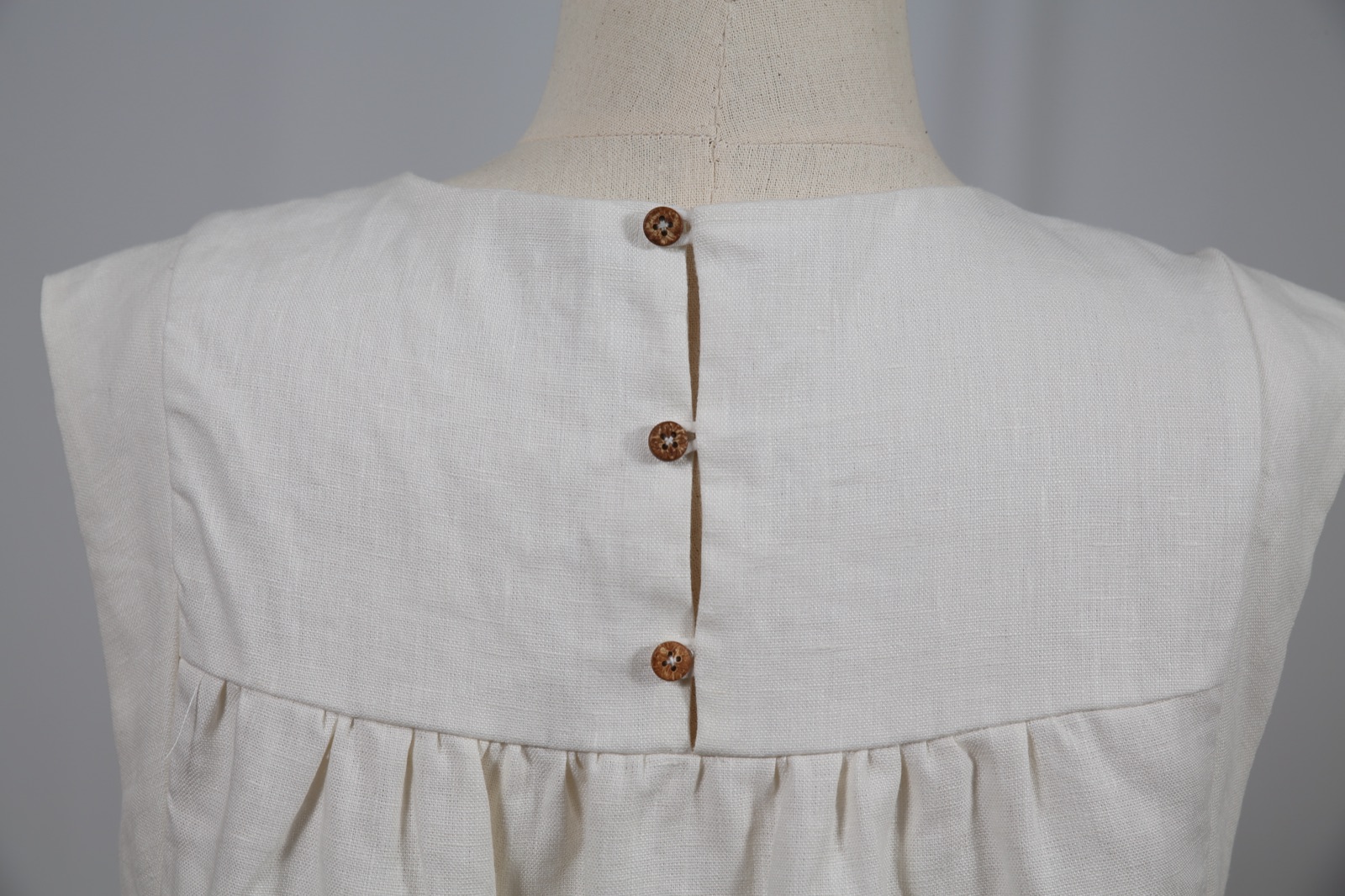 Back of a linen dress with three coconut buttons